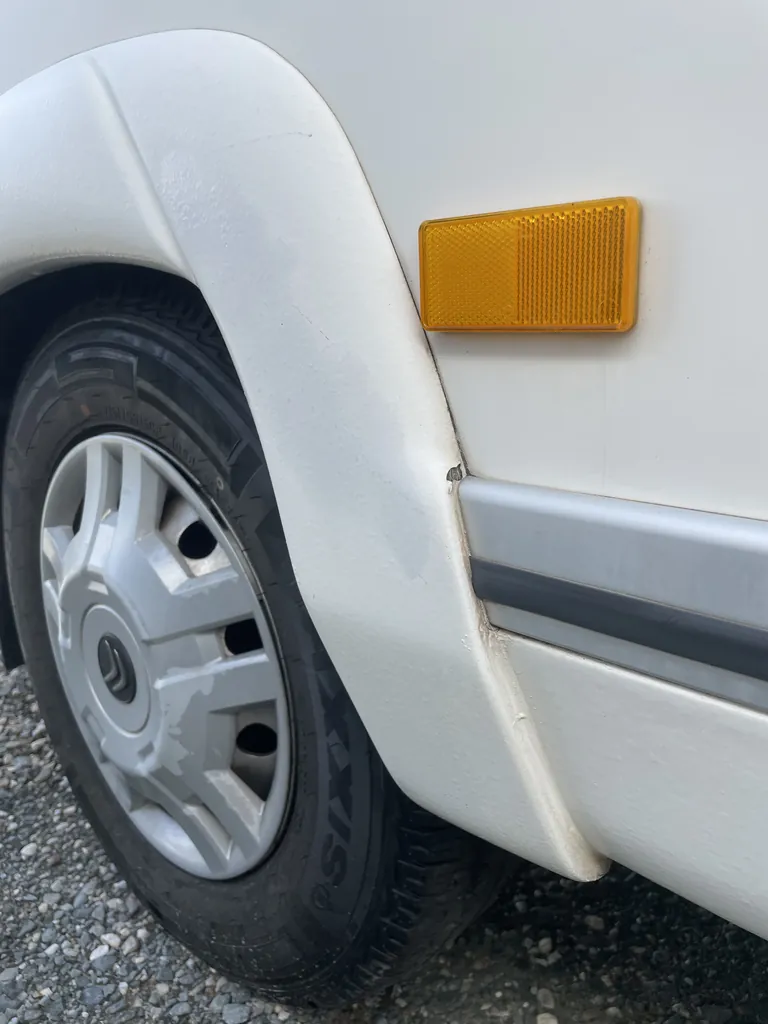 Aile avant d'un camping-car avec une fissure au bas du passage de roue