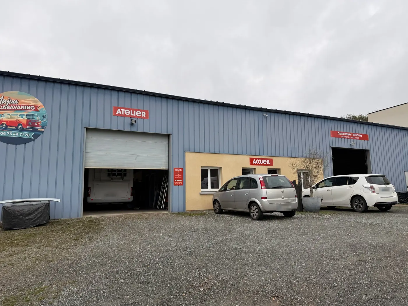 Façade de l'atelier Anjou Caravaning, avec l'enseigne ronde et l'inscription Carrosserie, Peinture, camping-car, auto, moto