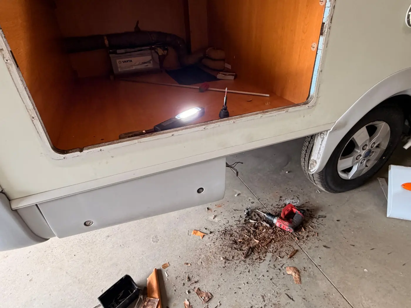 Bas de caisse d'un camping-car ouvert : bois et soubassement mis à nu pour contrôler l'état de la structure