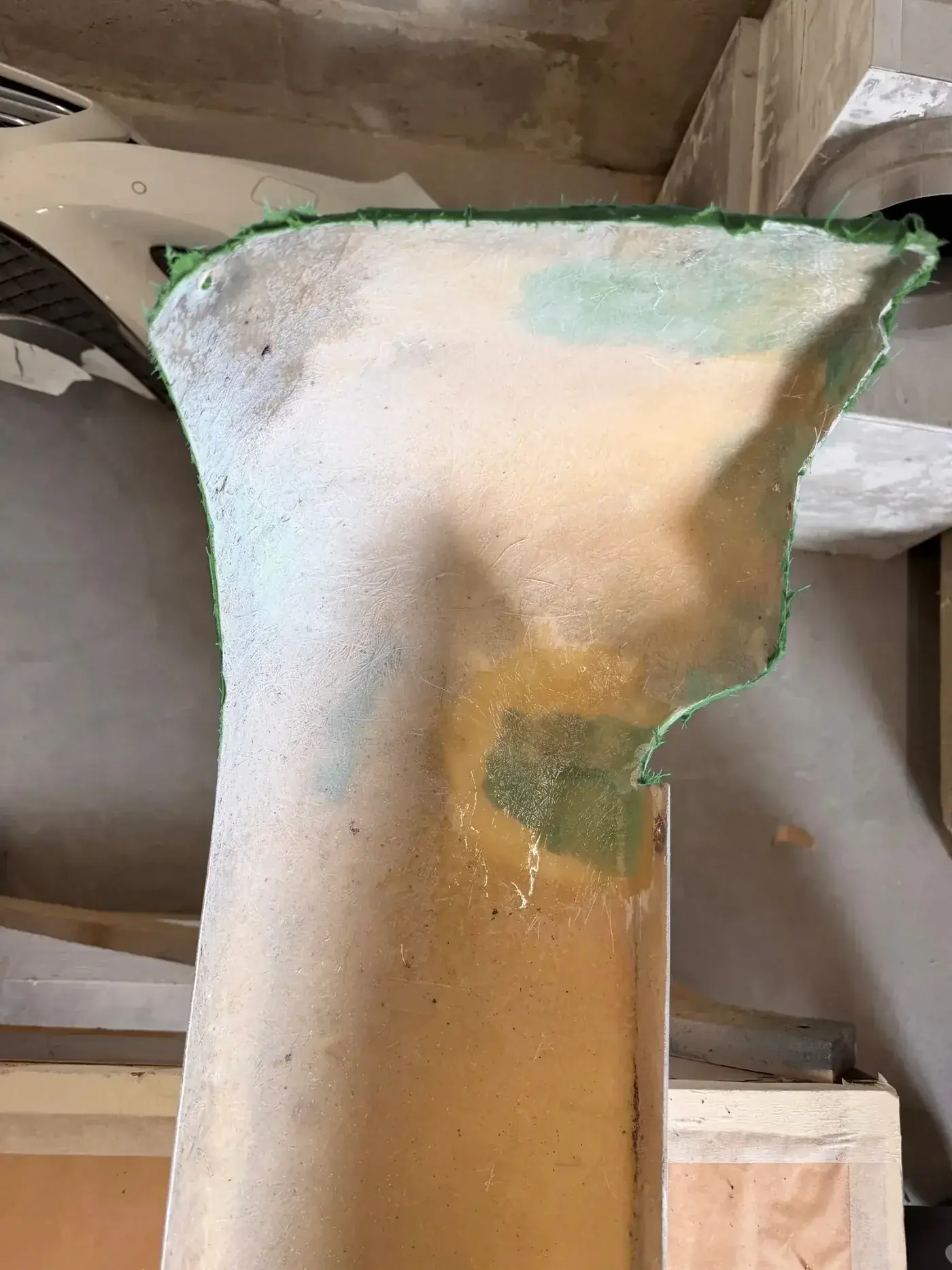Pièce de carrosserie en fibre en cours de réparation, avec le tissu de verre visible