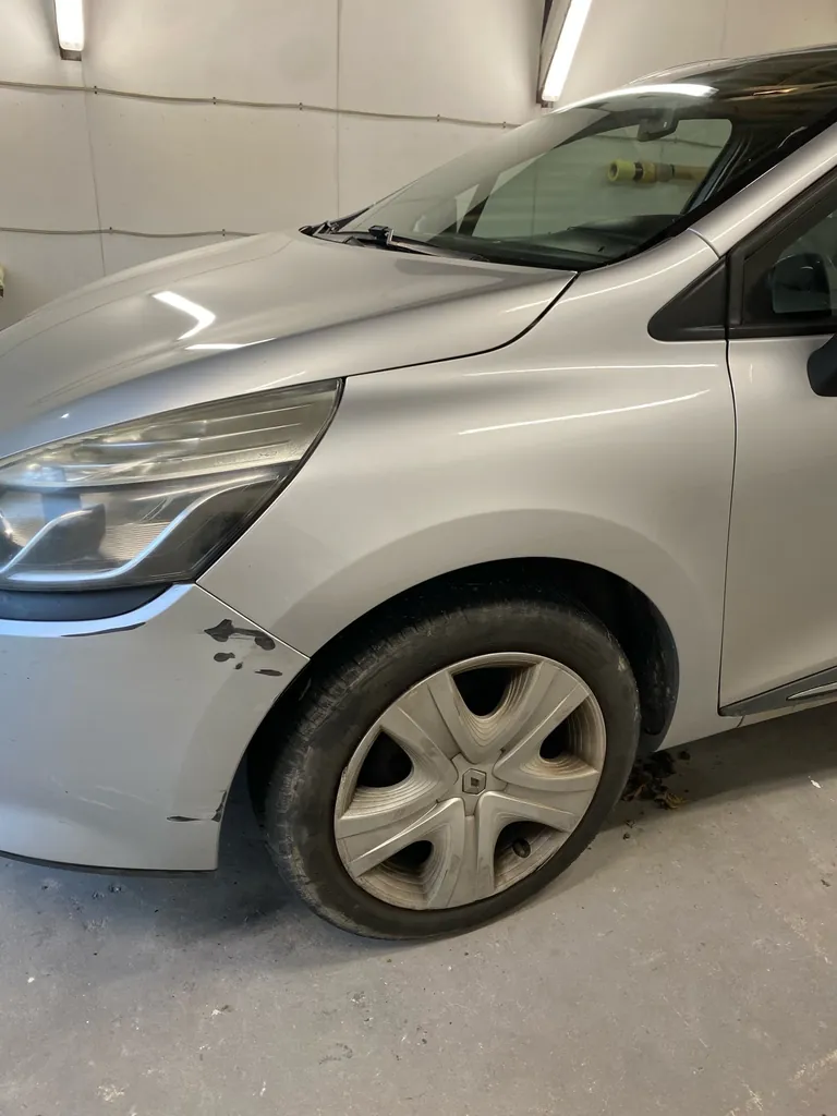 Voiture grise dans la cabine de peinture, vue d'ensemble de l'avant gauche